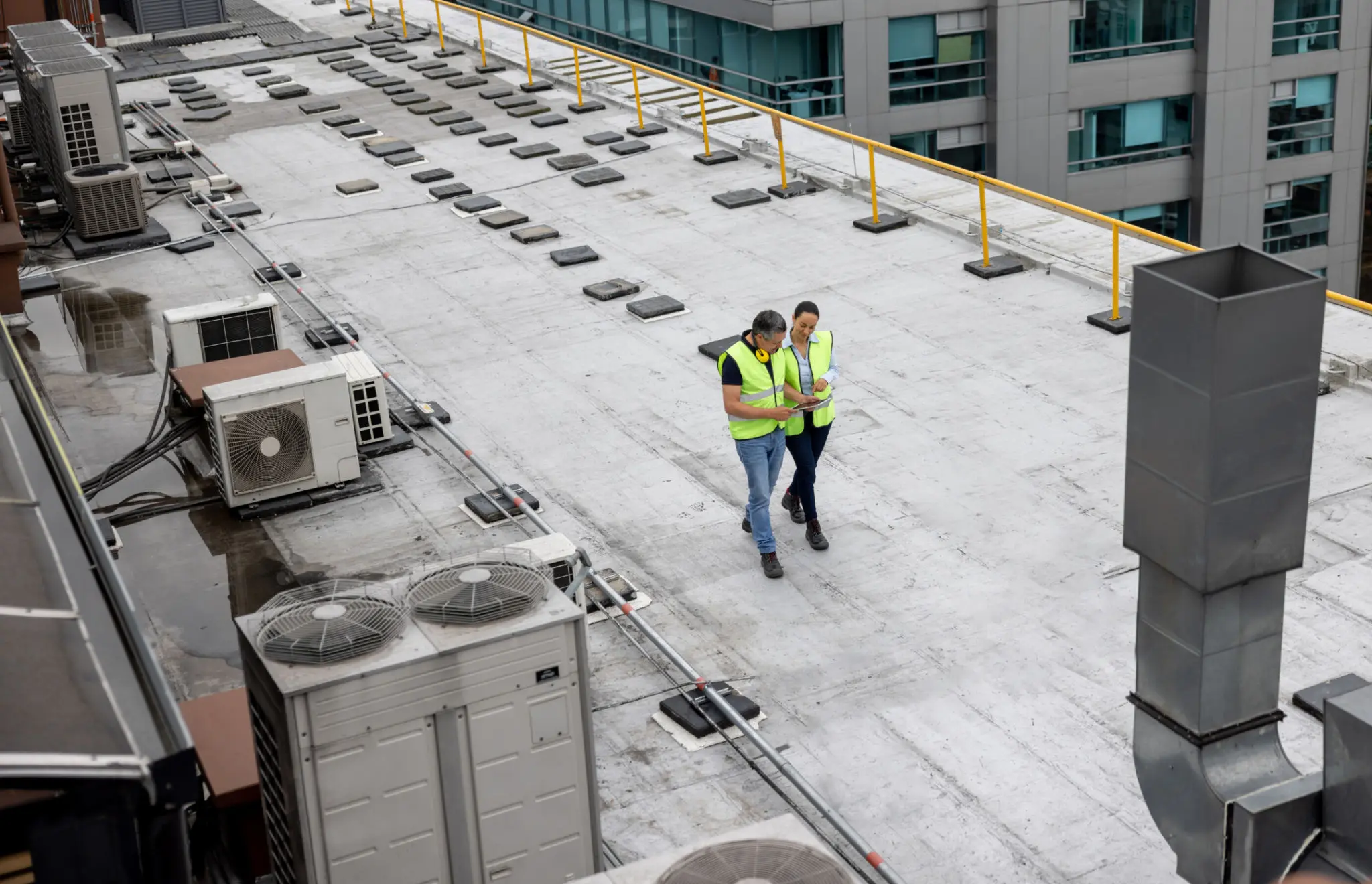 Two workers walking on a rooftop.