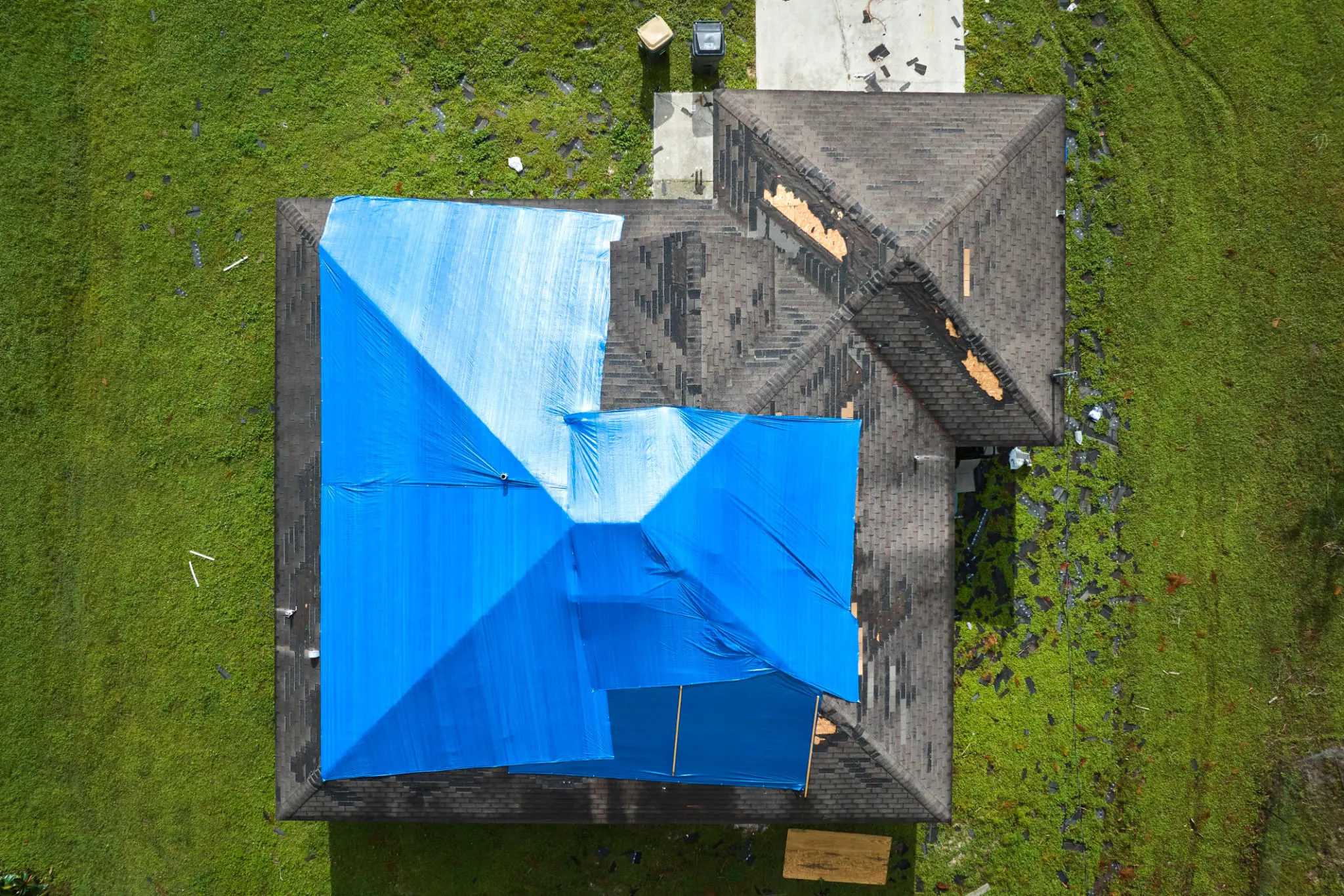 House roof with blue tarpaulin covering damage.