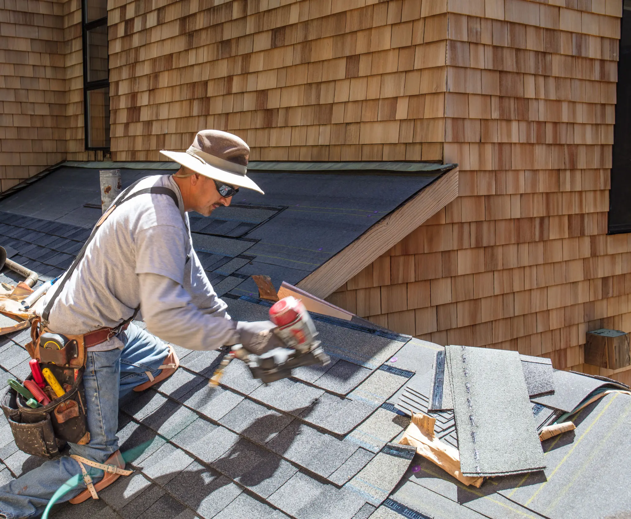 Roofer working on shingled roof installation.