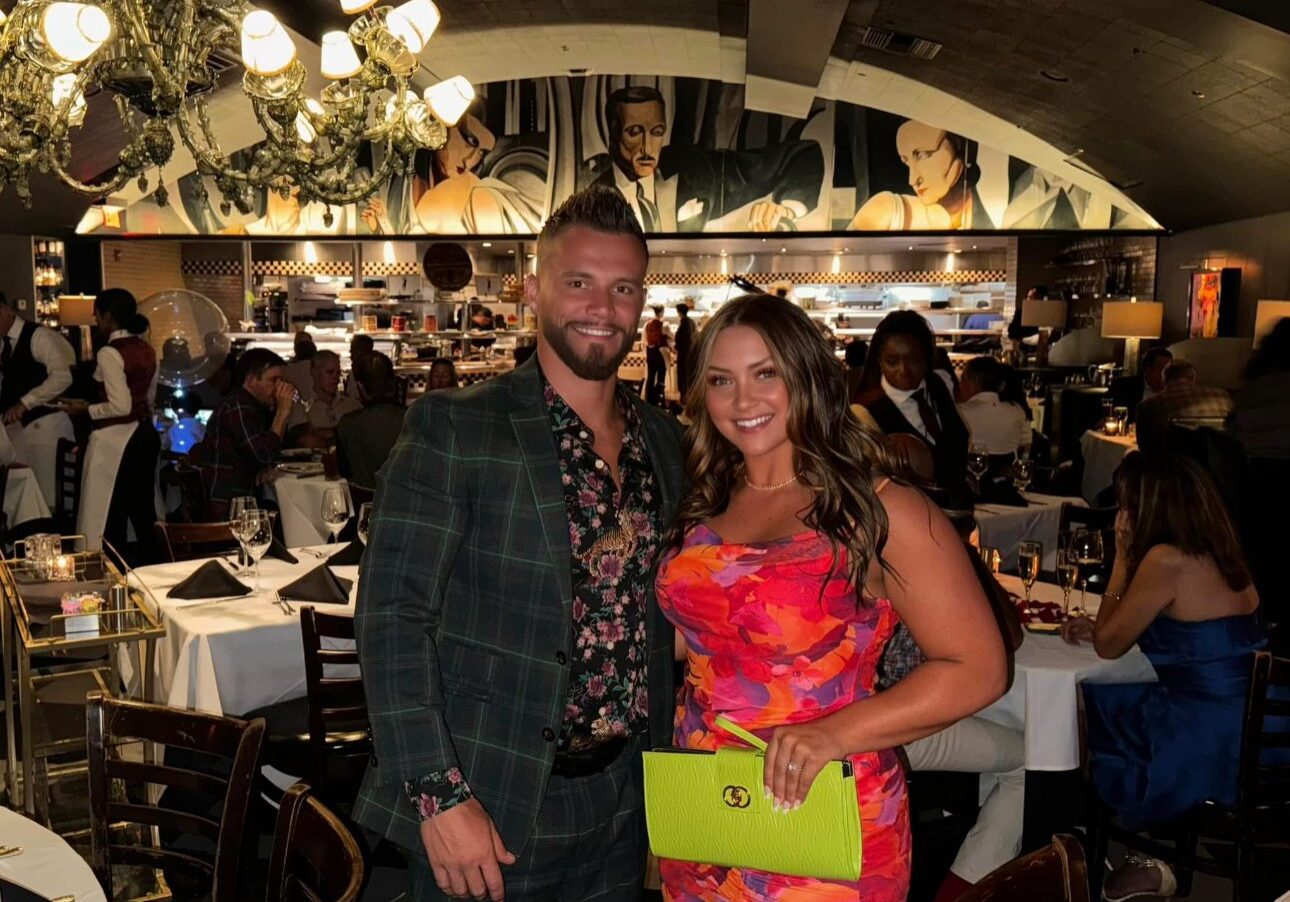 A man and woman posing together in a lively restaurant.